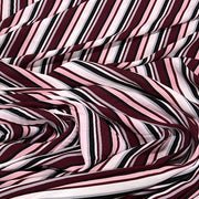 A close-up of draped striped fabric with alternating diagonal bands of burgundy, light pink, white, and black.