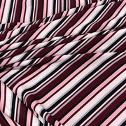 A close-up of draped striped fabric with diagonal bands in burgundy, pink, white, and black.