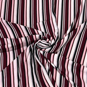 A close-up of striped fabric arranged in a spiral drape, showing alternating vertical stripes in burgundy, light pink, white, and black.
