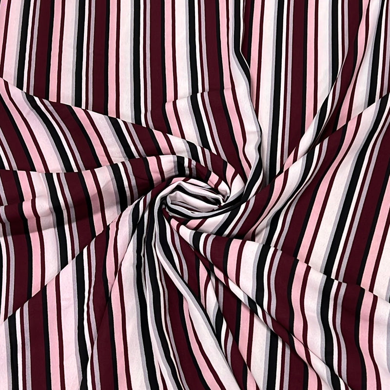 A close-up of striped fabric arranged in a spiral drape, showing alternating vertical stripes in burgundy, light pink, white, and black.
