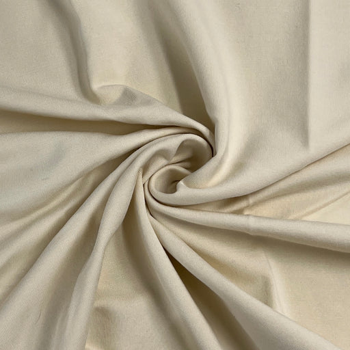 A close-up of draped cream-colored fabric arranged in a spiral swirl, showing its soft texture and folds.