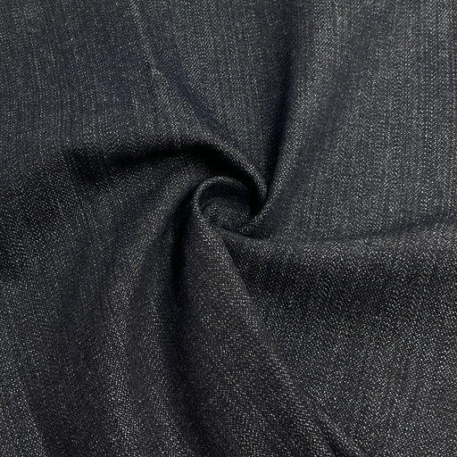 Closeup of dark indigo broken twill denim pulled into a swirl. 
