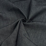 A close-up of dark indigo denim fabric, gathered in the center to show its weave and drape.