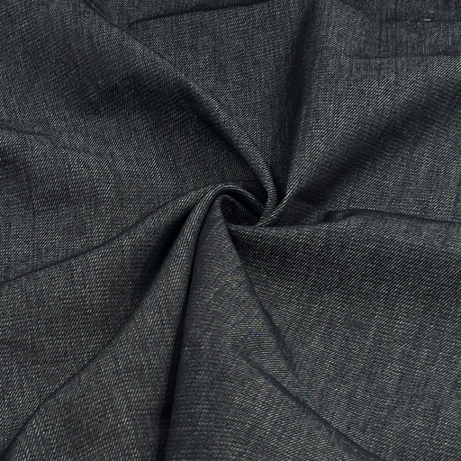 A close-up of dark indigo denim fabric, gathered in the center to show its weave and drape.