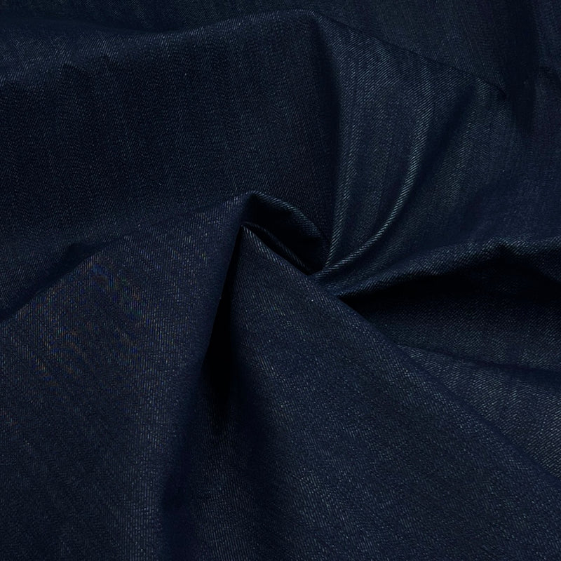 A close-up of dark indigo blue fabric with a subtle woven texture, gathered in soft folds.