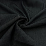 A close-up of dark charcoal gray fabric arranged in a spiral drape, showing its fine twill texture.
