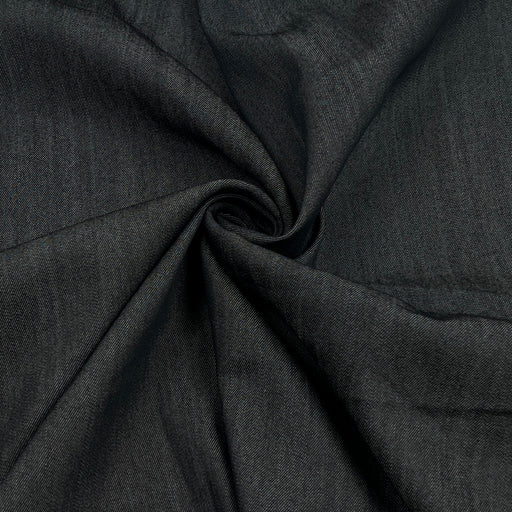 A close-up of dark charcoal gray fabric with a textured weave, arranged in a spiral drape to show its texture and flexibility.