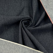 A close-up of dark indigo denim fabric with a diagonal twill texture, draped in a central swirl, with lighter gray fabric borders visible along the top right and bottom left edges.