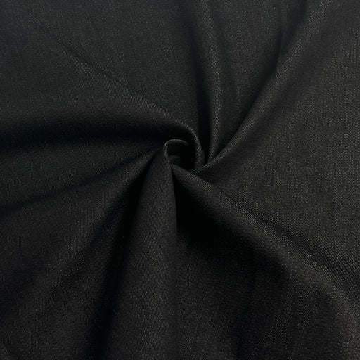 A close-up of draped black fabric with a textured weave, gathered in the center to show its drape and fine knit pattern.