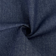 A close-up of dark indigo denim fabric with a textured twill weave, shown with a central swirl to highlight the material's drape and texture.