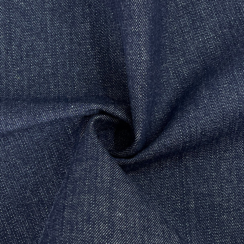A close-up of dark indigo denim fabric with a textured twill weave, shown with a central swirl to highlight the material's drape and texture.