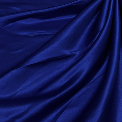 A close-up of draped royal blue satin fabric with soft folds and a subtle sheen.