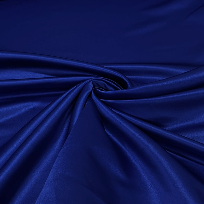A close-up of draped royal blue satin fabric with a glossy sheen and soft folds.