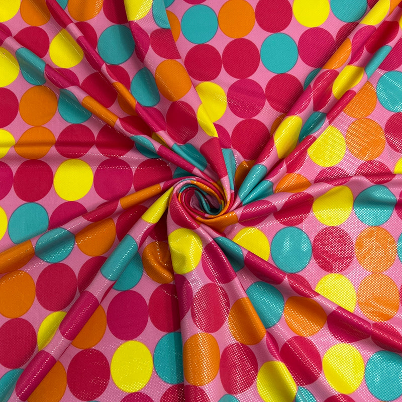 A close-up of a shinny pink fabric with a vibrant multicolor polka dot pattern, arranged in a spiral drape to show its texture and flow.