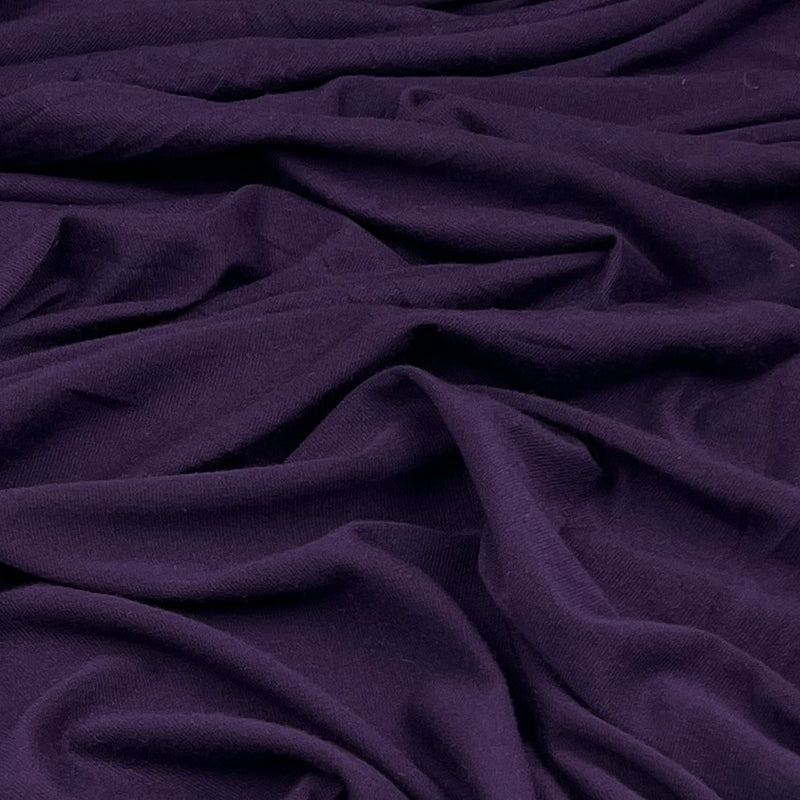 A close-up of draped dark purple fabric with soft folds and a smooth texture.