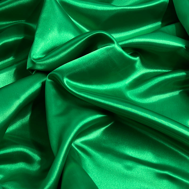 Green satin fabric with a glossy, lustrous sheen, draped in soft folds.