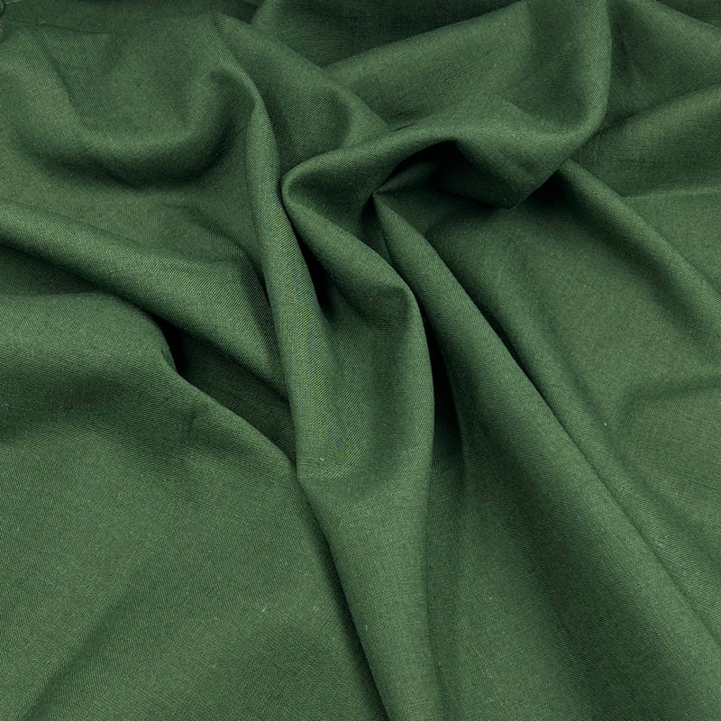 A close-up of draped forest green linen fabric with soft folds and a smooth texture.