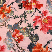 A close-up of a pink patterned fabric or wallpaper featuring watercolor-style red and orange flowers with green and gray-blue leaves on black branches.