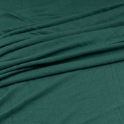A close-up of draped dark teal green fabric with soft folds and a smooth texture.