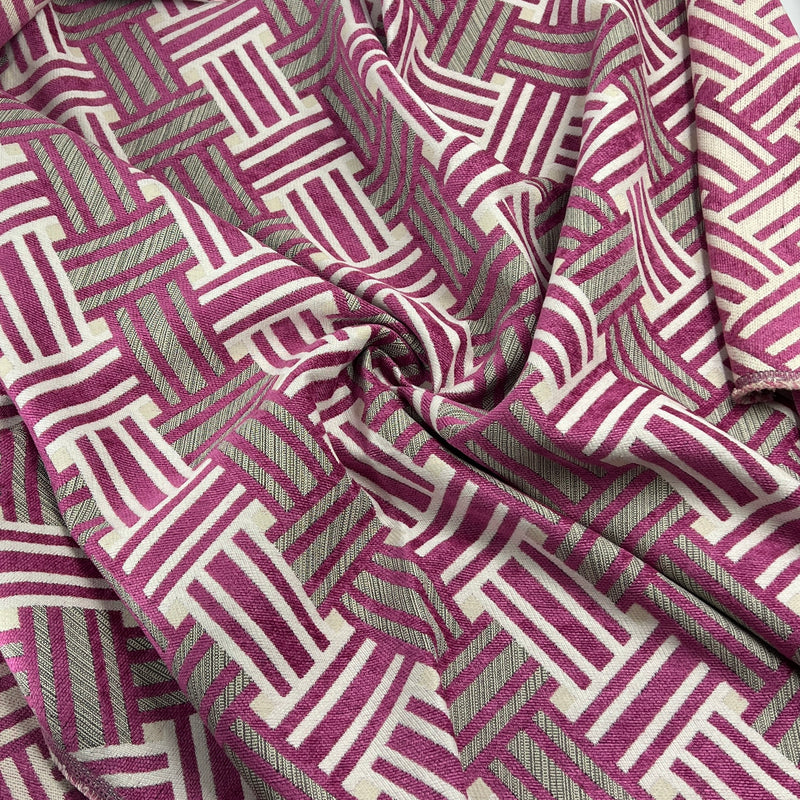 A close-up of draped fabric with an allover geometric basketweave pattern in magenta pink and off-white.