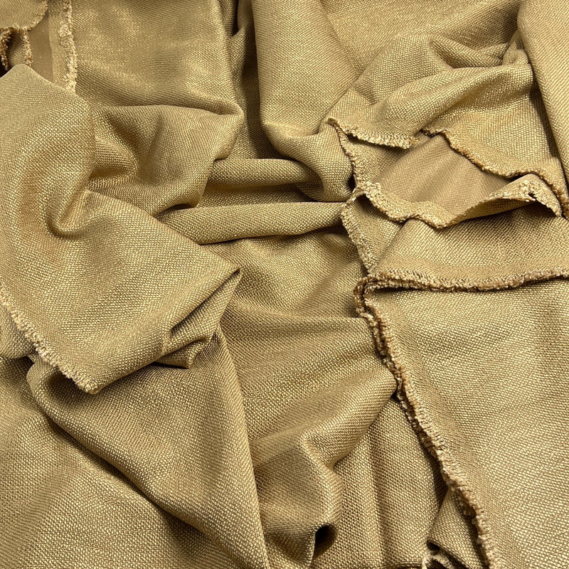A close-up of draped tan woven fabric with frayed, raw edges, showing a textured linen-like surface.