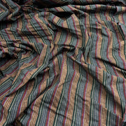 A close-up of draped striped fabric with vertical bands in brown, beige, muted red, and dark gray, featuring small white dotted accents.