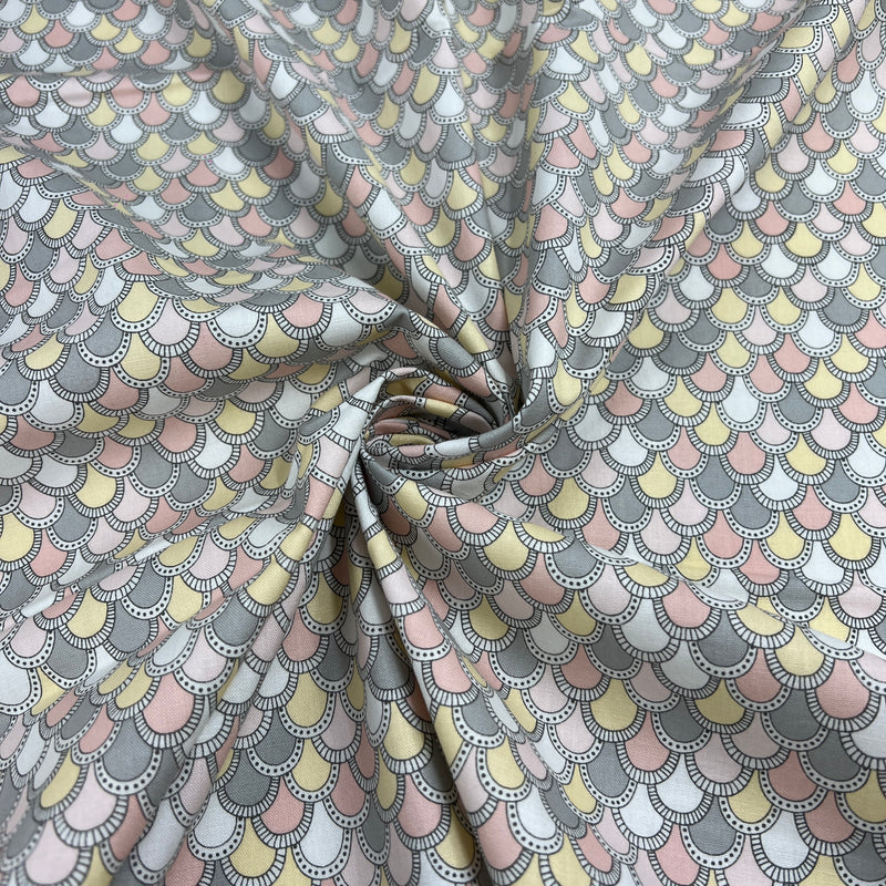 A close-up of patterned fabric swirled in the center, showing a repeating scallop or fish-scale design in soft gray, dusty pink, pale yellow, and white.