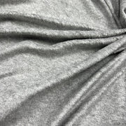 A close-up of draped heather gray fabric with soft folds and a textured knit or jersey surface.