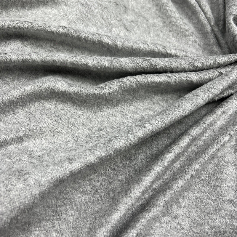 A close-up of draped heather gray fabric with soft folds and a textured knit or jersey surface.
