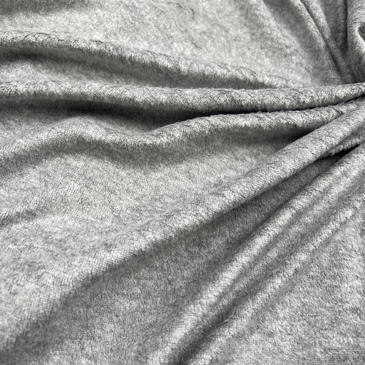 A close-up of draped heather gray fabric with soft folds and a textured knit or jersey surface.