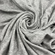A close-up of light gray heathered fabric arranged in a spiral drape, showing the soft texture and weave of the material.