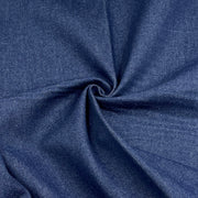 A close-up of dark blue denim fabric with a textured twill weave, arranged in a spiral drape to show its texture and color.