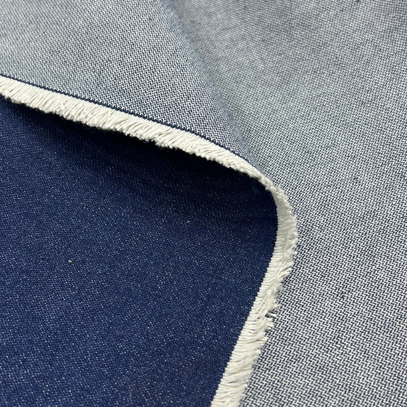 A close-up of fabric showing two colorways: a light gray woven texture with a white frayed edge, and a dark navy blue woven texture. The fabrics are layered to show both sides of the material.