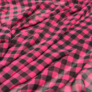 Chiffon fabric with a hot pink checkered pattern draped over a white background.