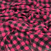 A close-up of draped fabric with a bold pink and black buffalo plaid pattern.