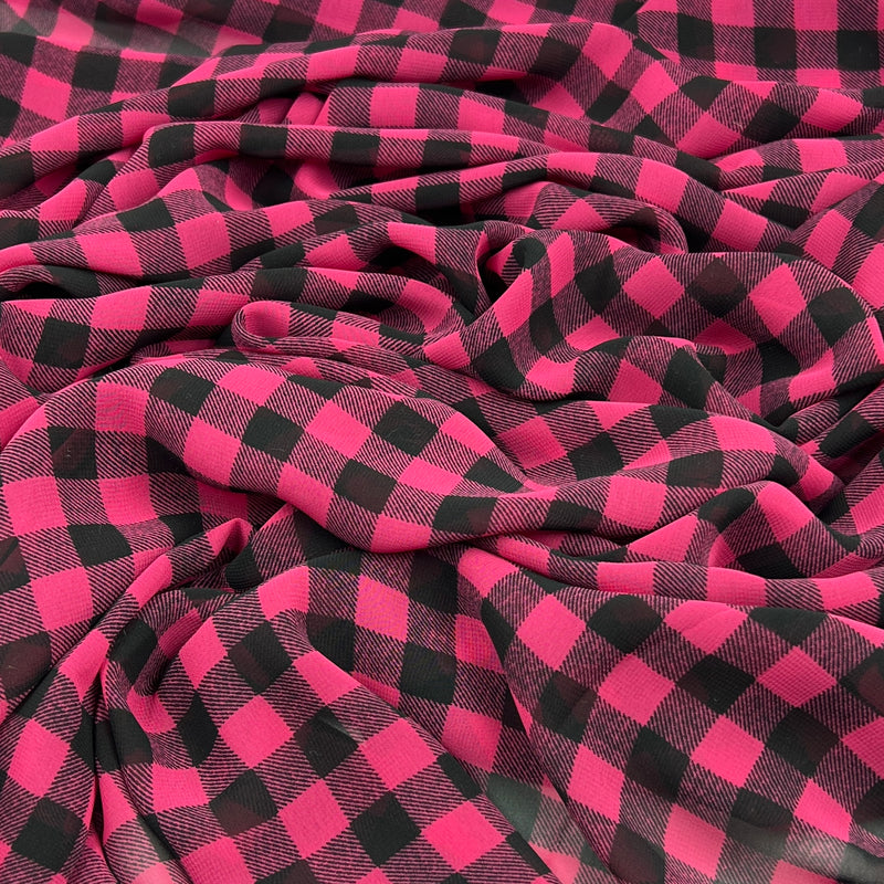 A close-up of draped fabric with a bold pink and black buffalo plaid pattern.