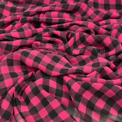 A close-up of draped fabric with a bold pink and black buffalo plaid pattern.