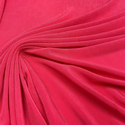 A close-up of bright pink fabric with soft folds and a smooth texture filling the frame.