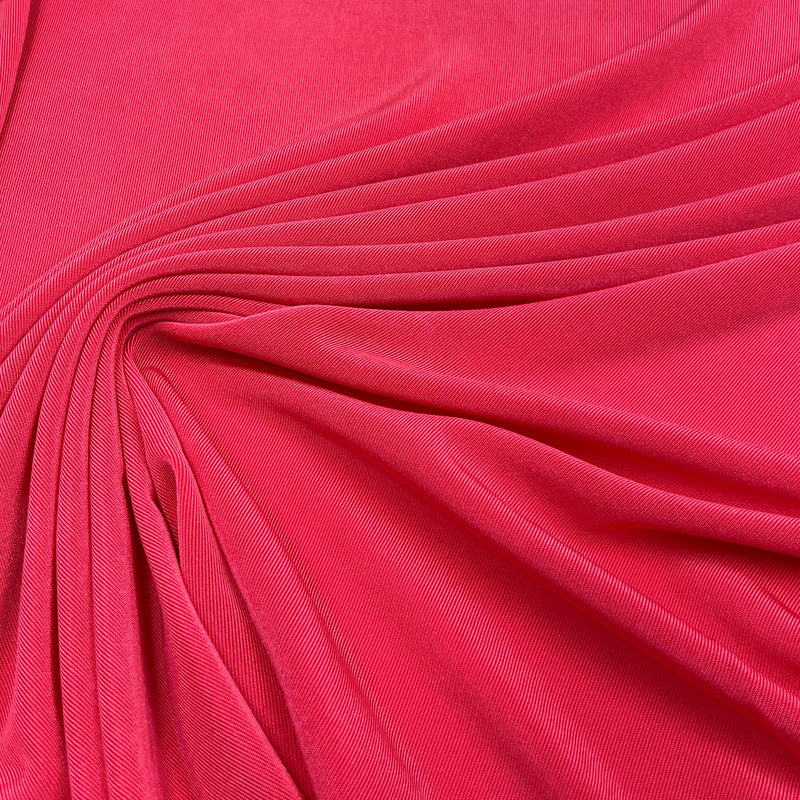 A close-up of bright pink fabric with soft folds and a smooth texture filling the frame.