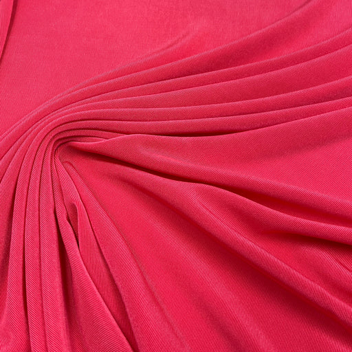 A close-up of bright pink fabric with soft folds and a smooth texture filling the frame.
