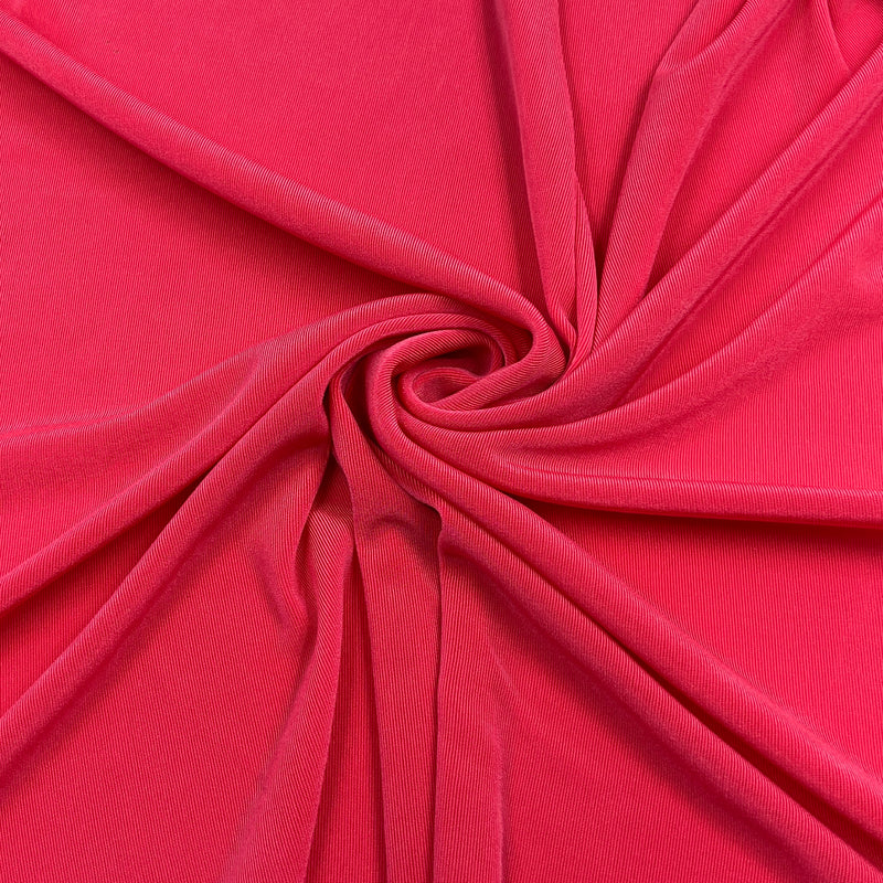 A close-up of bright pink fabric arranged in a spiral drape, showing the material's texture and color.