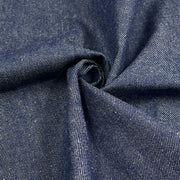 A close-up of dark indigo denim fabric with a twisted center, showing the detailed twill weave texture.