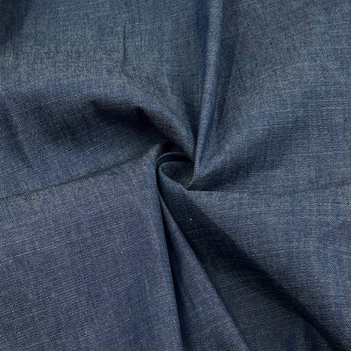 A close-up of dark blue textured fabric with a twisted fold in the center, showing the material's weave and color.