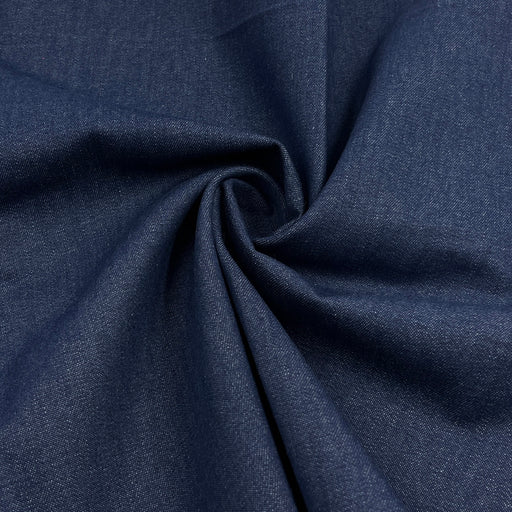 A close-up of dark navy blue fabric with a textured weave, arranged in a spiral drape to show its texture and flexibility.