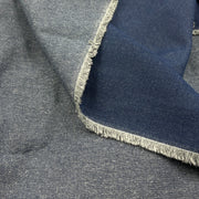 A close-up of folded fabric with a heathered medium gray outer side and a darker navy inner side, finished with frayed edges.