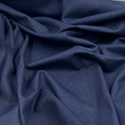 A close-up of draped indigo blue fabric with soft folds and a smooth texture.