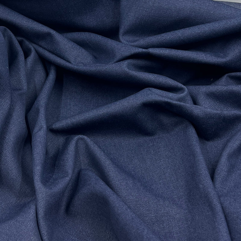 A close-up of draped indigo blue fabric with soft folds and a smooth texture.