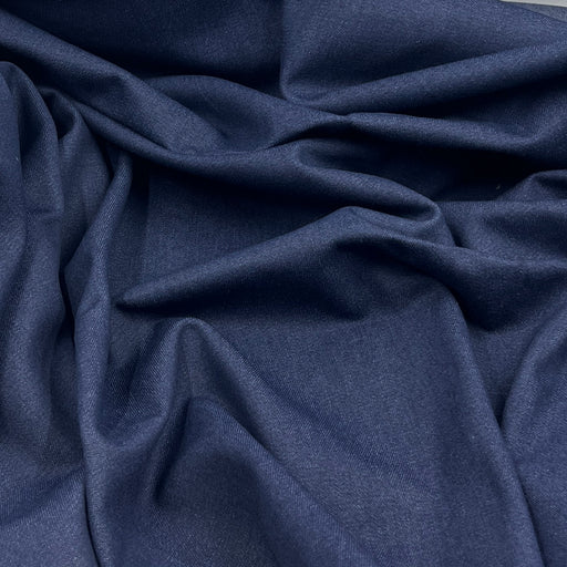A close-up of draped indigo blue fabric with soft folds and a smooth texture.