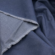 A close-up of folded dark blue fabric with a visible lighter blue frayed edge, showing the material texture and color variation.