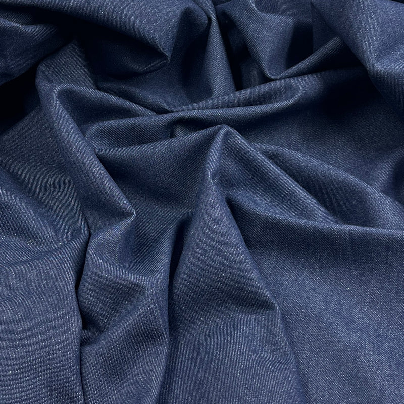 A close-up of draped navy blue fabric with a fine textured weave, showing soft folds and shadows.